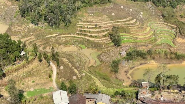 Tilt up view from rural village and pond rising toward hillside temple complex in Quan Ba Ha Giang Vietnam landscape