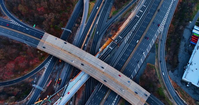 Crossing flyover bridges above a highway under construction, New Jersey. Top-down of intersecting elevated roadways with active bridge construction and equipment between traffic lanes