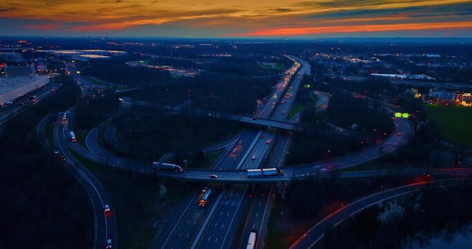 Highway interchange at twilight with sweeping ramps, New Jersey. Elevated dusk view of looping roadways and a flyover with faint traffic lights threading through dark woodland