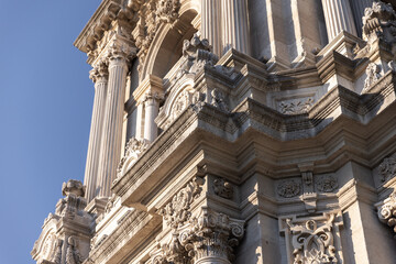 Close-up of an ornate classical building facade showcasing carved stone columns, intricate ornamentation and deep shadows that highlight historic craftsmanship of Dolmabahce Clock Tower built in 1895 © evannovostro