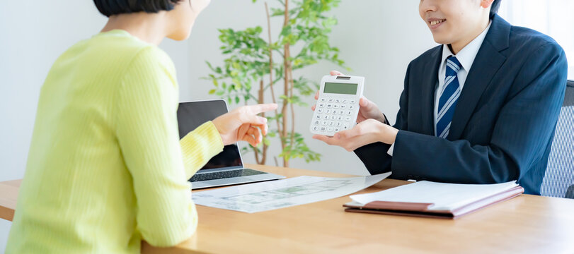 電卓を見せる不動産営業マンと女性
