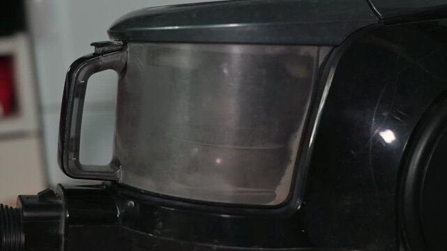 A close-up view shows the process of cleaning a vacuum cleaner container. The setting highlights the cleaning activity, focusing on the container's details and the cleaning tools involved