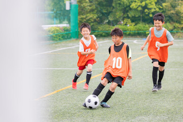 Naklejka premium ドリブルの後シュートでゴールを狙うサッカー少年たち
