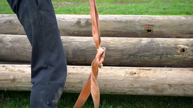 Strong men lifting up a big tree trunk in a pile with an extra helping band and then pushing it with a leg in place