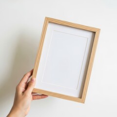 Fototapeta premium Woman hand holding a wooden picture frame for mockup presentation