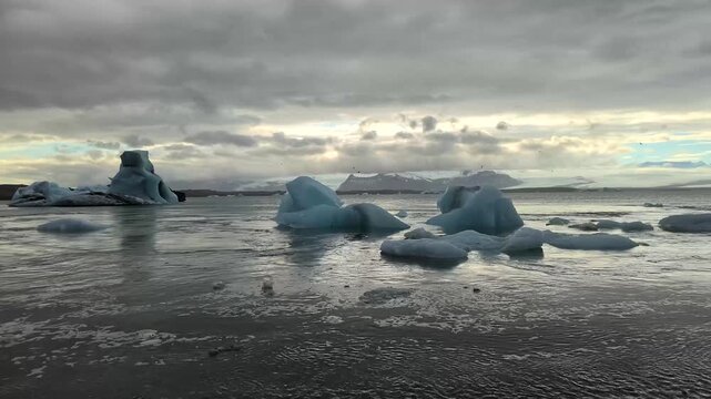 Icebergs d&eacute;rivant sur un lac glaci&egrave;re en Islande. Une nu&eacute;e d'oiseaux vole au dessus de l'iceberg. Symbole du r&eacute;chauffement climatique