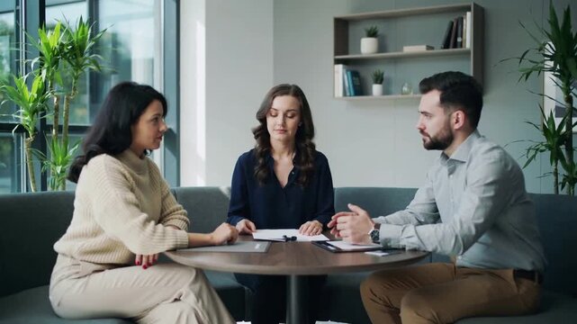Reviewing documents in office, three colleagues in smart attire discussing, clarifying terms, phone