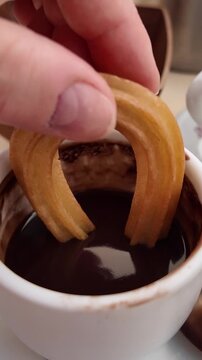 Churros, traditional, fatty Spanish pastry in the form of a long rod with a star-shaped cross-section, served with hot chocolate. Vertical view.