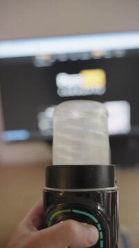Male hand holding and activating an electronic adult sex toy with a digital display in a room