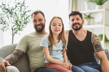 Obraz premium homosexuals gay couple love each with his lovely adopt little girl on sofa