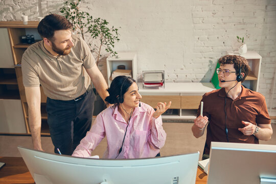 Support agents discussing service escalation with supervisor. Concept of customer complaint resolution, call center teamwork, service coaching, helpdesk review, and issue management.