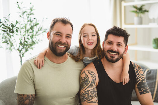 homosexuals gay couple love each with his lovely adopt little girl on sofa