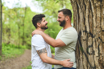 Fototapeta premium A Portrait of a happy gay couple outdoors in forest background