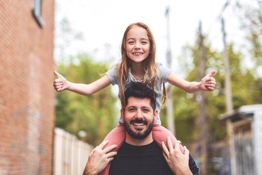 A Portrait of a happy gay couple outdoors in urban background with his adopt little girl