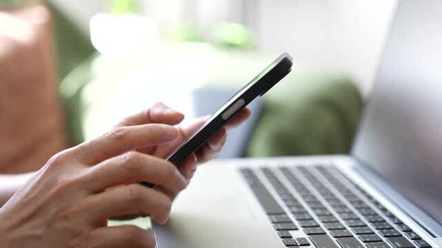 close up smartphone usage scenes with laptop workspace, representing mobile banking, digital payment, online communication, fintech applications and modern digital lifestyle technology.