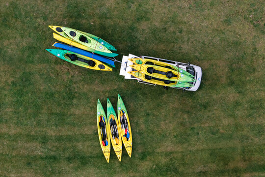 Aerial view of a white van and trailer loaded with colorful kayaks parked on a green grassy field in Kaunas, Kaunas County, Lithuania.