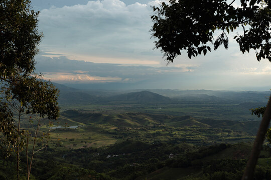 Beautiful mountain valley at dusk framed by tree branches in Sevilla Valle del Cauca, Colombia