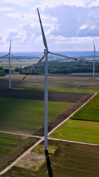 Aerial vertical view of view of large fields with electric windmills in the afternoon sun