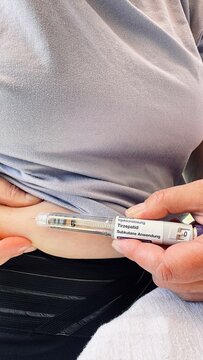 Woman injecting subcutaneous medication in abdomen with disposable pen device