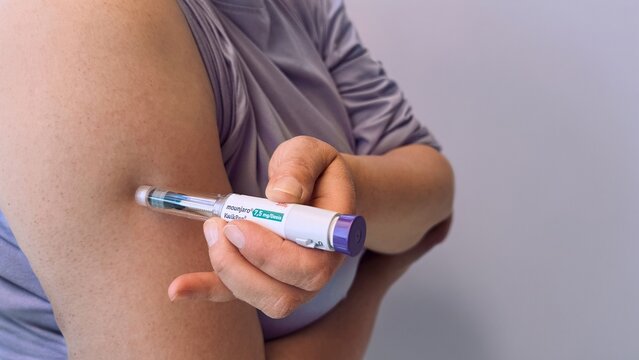 Woman injecting diabetes medication with pen in upper arm during self care