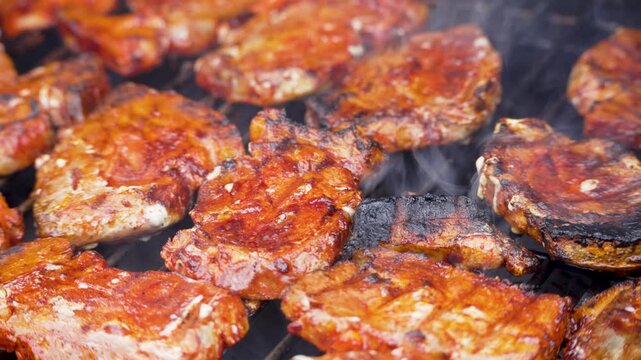 Glazed pork steaks cook closely together on a hot grate. Smoke and char marks create a hearty barbecue video preview.