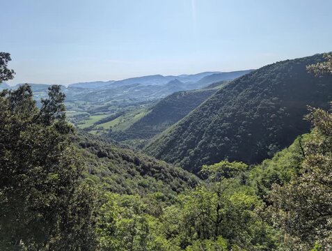 Una vasta e profonda vallata si estende a perdita d'occhio tra imponenti dorsali montuose ricoperte di boschi. 