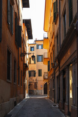 Naklejka premium Narrow Cobblestone Alley Framed by Historic Warm Colored Buildings with Green Shutters in Verona Italy