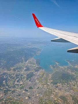 April 25, 2026: An aerial view from the window showing the wing and red winglet of an Eastar Jet Boeing 737 passenger airplane flying over the blue ocean.