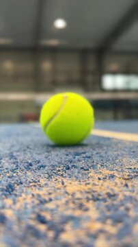 Rolling padel tennis ball on blue court surface near net, close up sports footage for racket game and training concepts