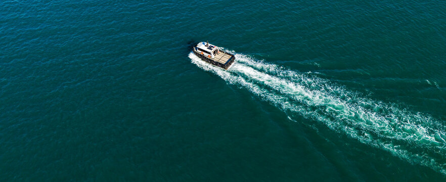 Overhead aerial of a small pilot boat speeding and leaving a prominent white wake