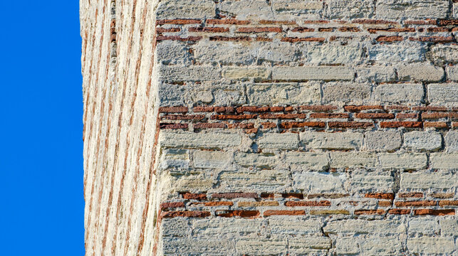 Straight edge of a weathered historical brick and stone wall meeting the sky