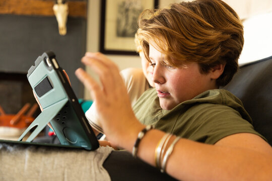 12 year old boy using tablet computer for gaming