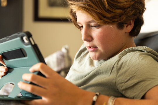 12 year old boy using tablet computer for gaming