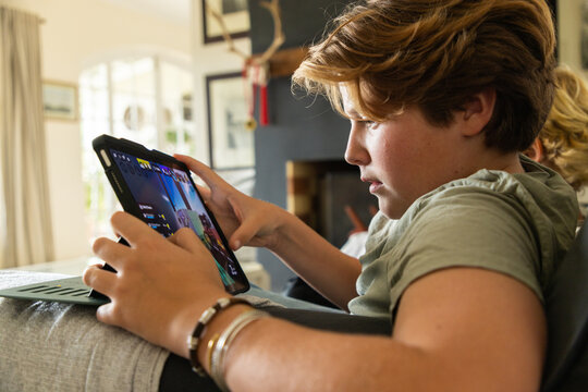 12 year old boy using tablet computer for gaming