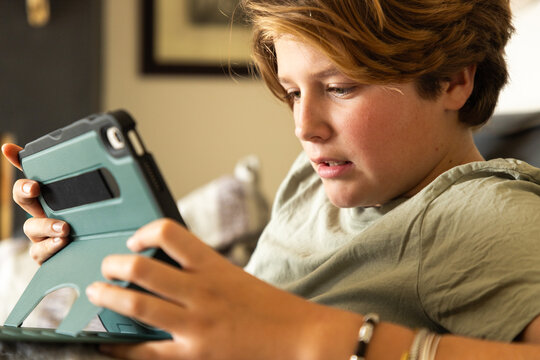 12 year old boy using tablet computer for gaming