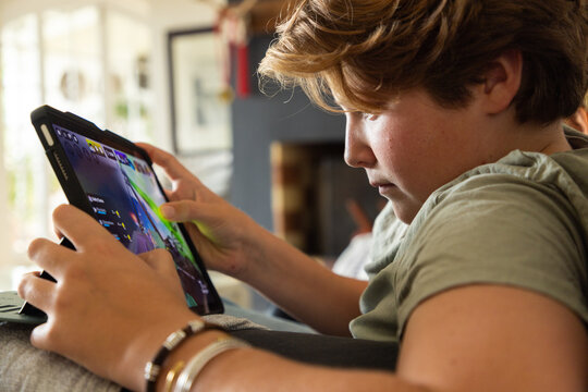 12 year old boy using tablet computer for gaming