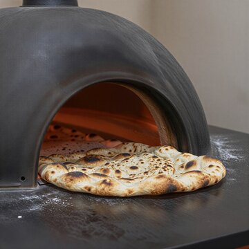 Fresh flatbread baking on a traditional saj oven