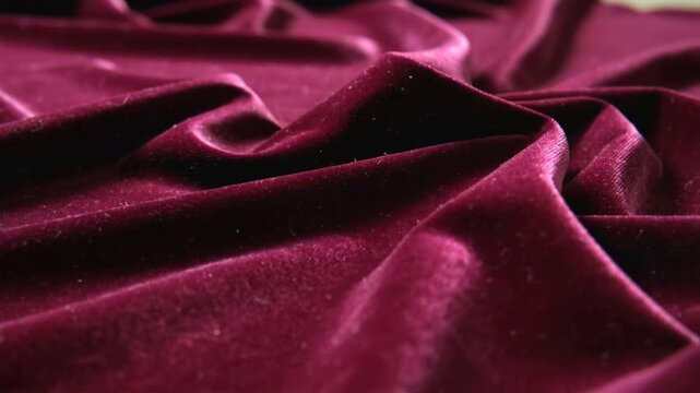 Panning camera shifting focus, burgundy velvet showing folds, lint in studio, revealing texture