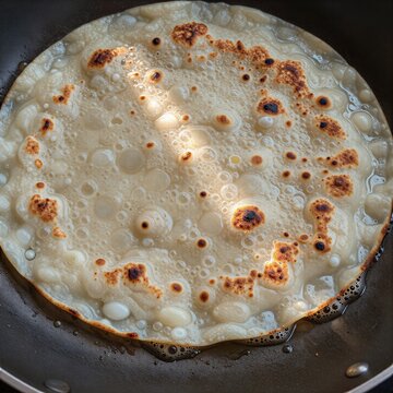 Bammy cassava flatbread frying in a pan