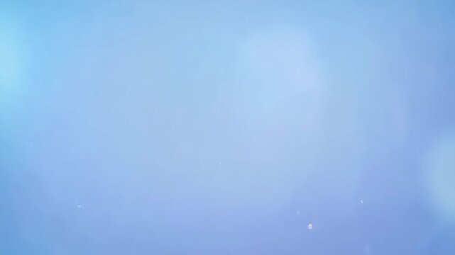 Soft clean blue sky with very light white gradient and subtle sun flare effect. Concept of peaceful clear weather and space for text templates