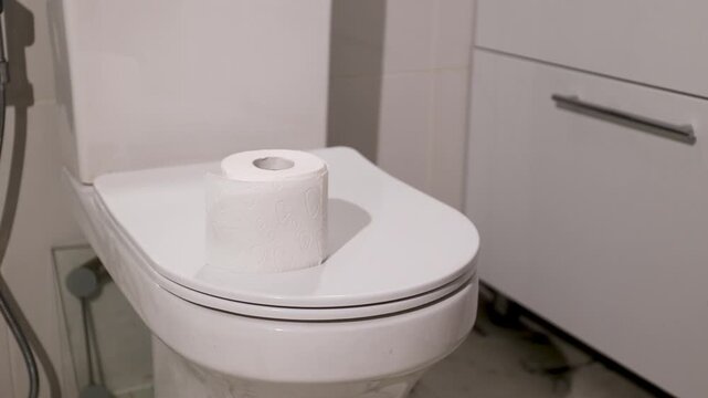 Woman putting toilet paper roll on restroom bowl. Hygiene maintenance for intestinal health and prevention of discomfort. Medical awareness for screening of hemorrhoid and colorectal cancer symptoms.