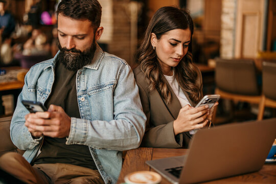 Couple ignoring each other while using smartphones in cafe