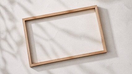 Fototapeta premium Slim wooden frame on a textured white surface, showcasing natural shadows and minimalist design.