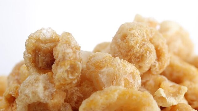 Pile of crispy pork rinds rotating slowly on a white background. Close-up view