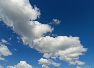 Fototapeta premium Beautiful white fluffy cumulus clouds in a vibrant deep blue sky.
