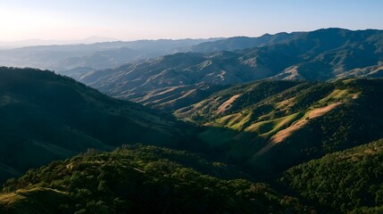 Obraz premium An aerial view of rolling mountains bathed in warm evening light creating a serene and majestic landscape