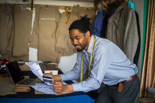 Photo showing african american tailor making online payment with credit card -stock photo