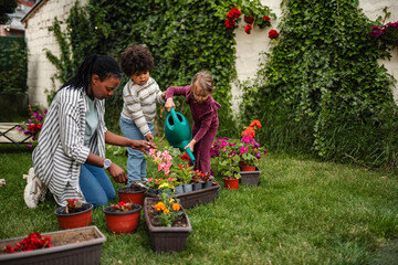 Fototapeta premium Mother and children planting flowers together in garden