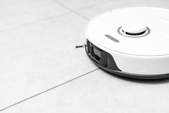 robot vacuum cleaner in modern smart home, robotic vacuum cleaner on tiles floor, Robot vacuum cleaner cleaning dust on tile floors. Modern smart cleaning technology housekeeping