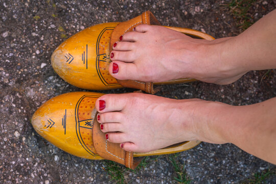 Feet of dutch woman resting on traditional wooden clogs, dutch culture, lifestyle and heritage concept